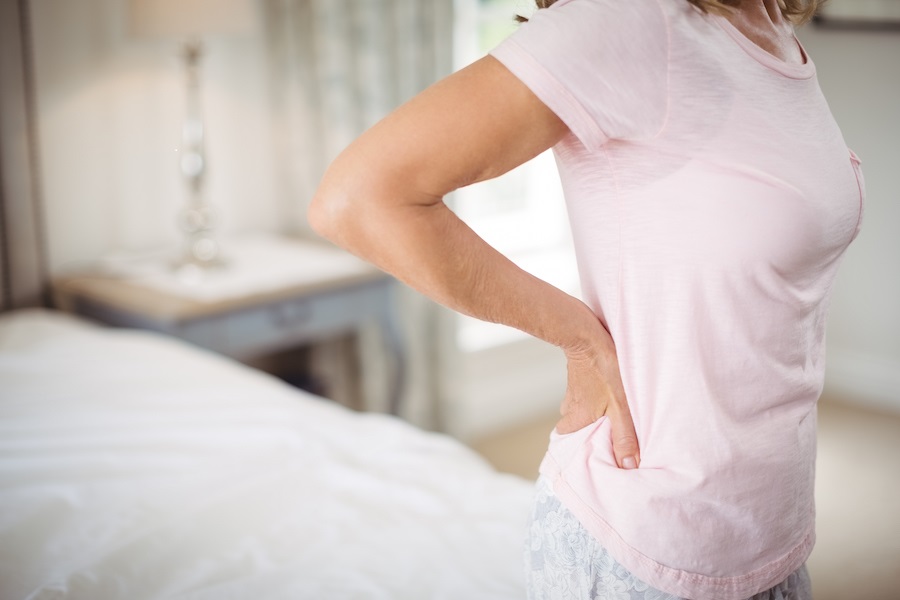 Senior woman having back pain in bedroom